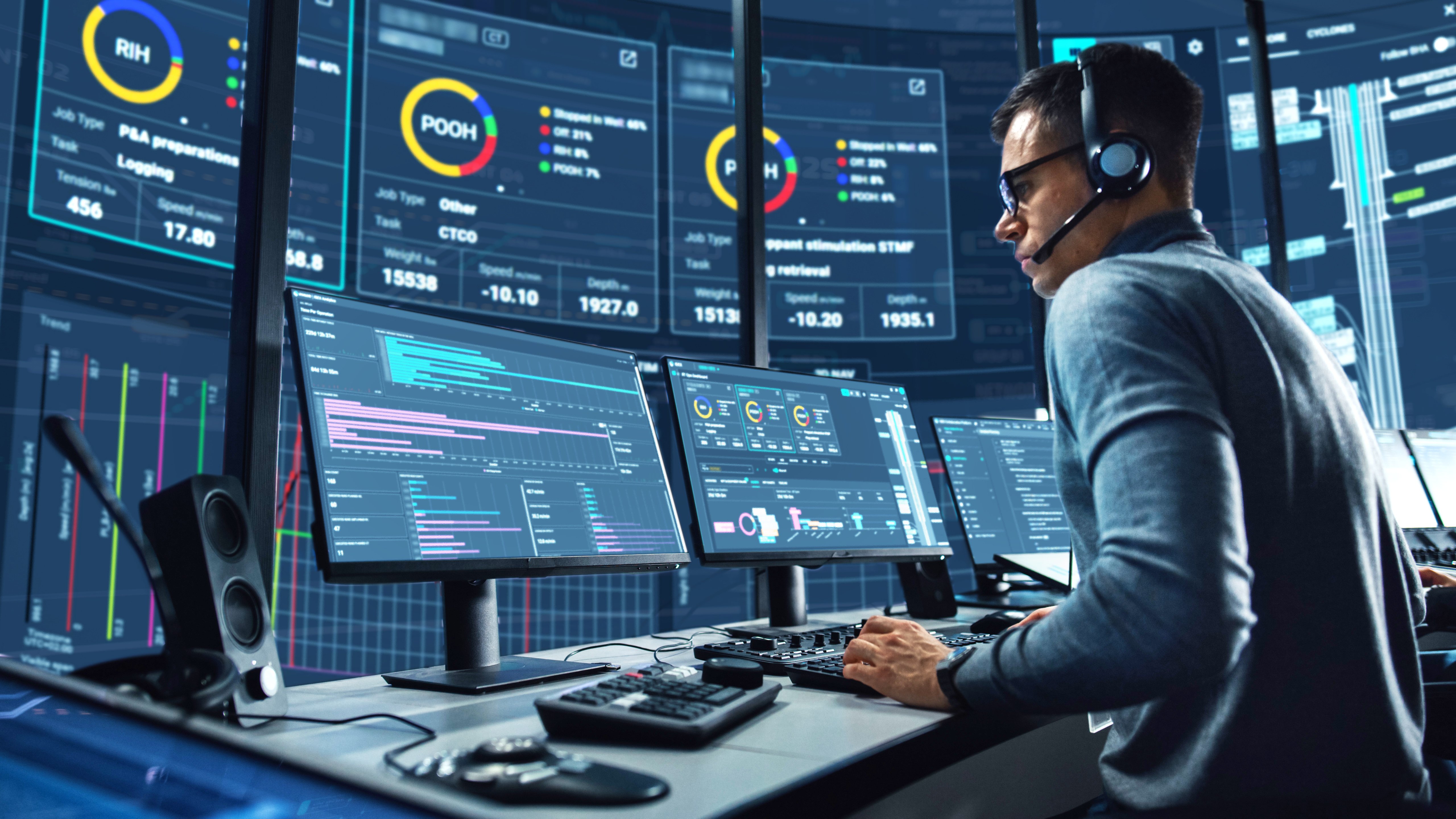 Engineer in a digital operations center monitoring coiled tubing and wireline automation dashboards with real-time well data.