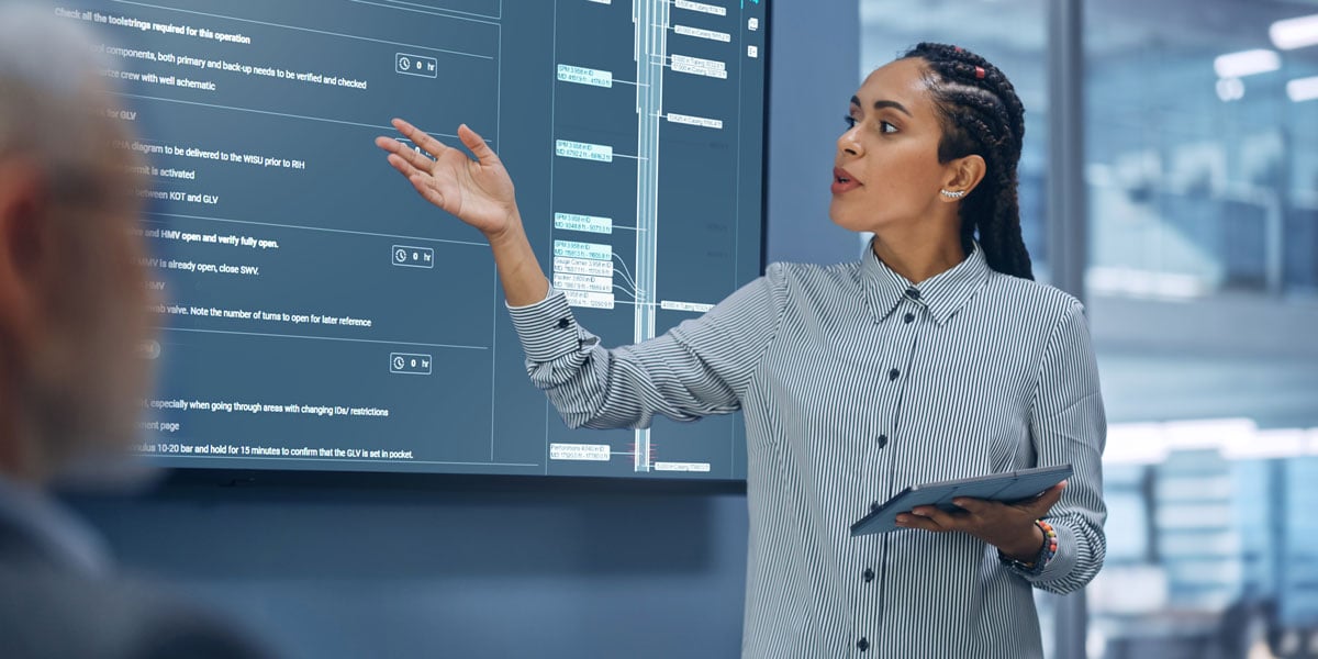 Engineer presenting well operation data on a digital dashboard while analyzing automated tracking and NPT reporting software performance.