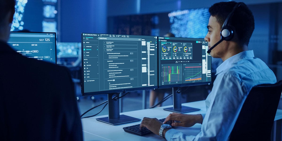 Engineer overseeing real-time drilling and well operations on dual monitors displaying digital performance dashboards and workflow software.